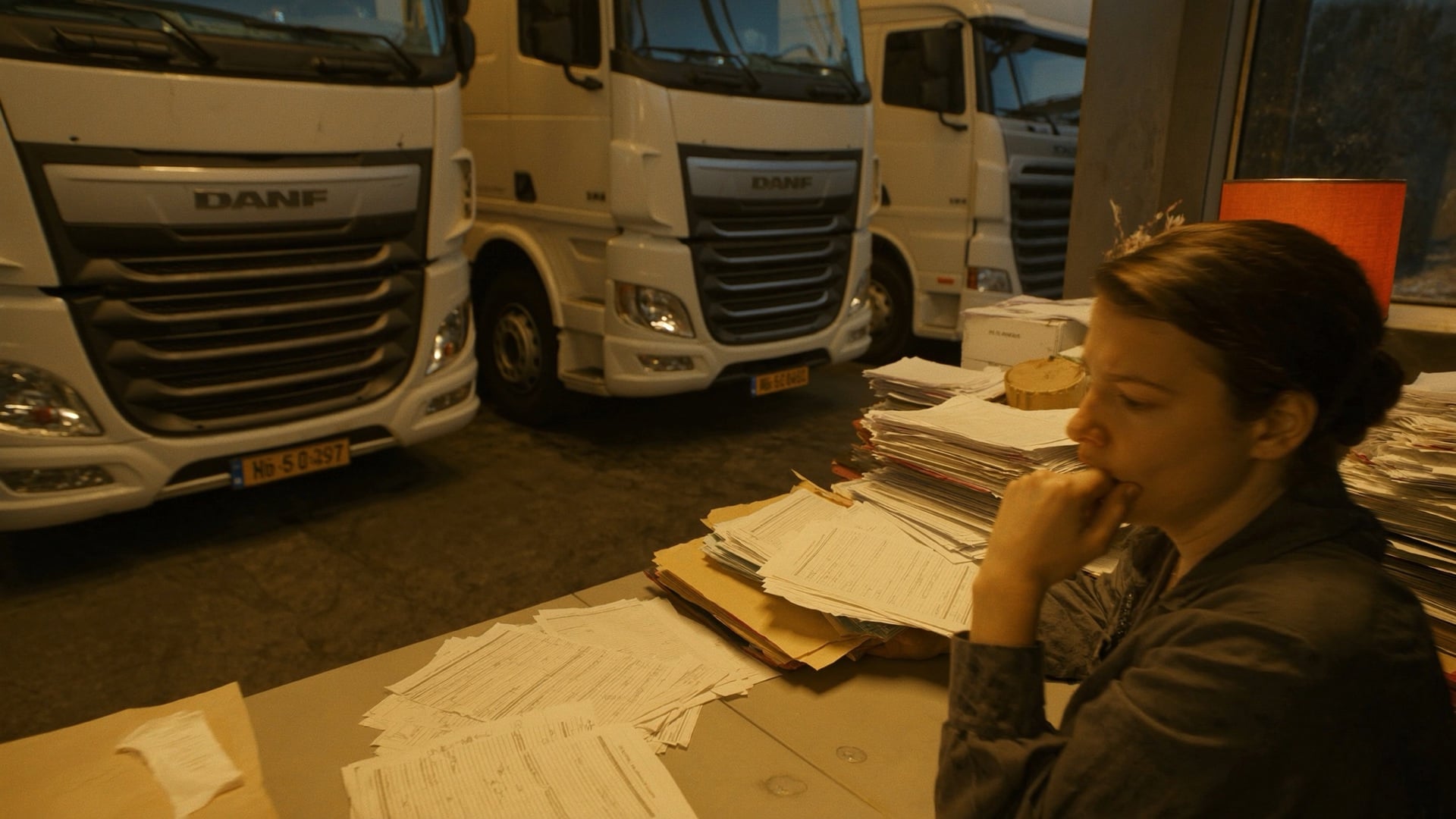 Back-office coordinator surrounded by billing paperwork late at night