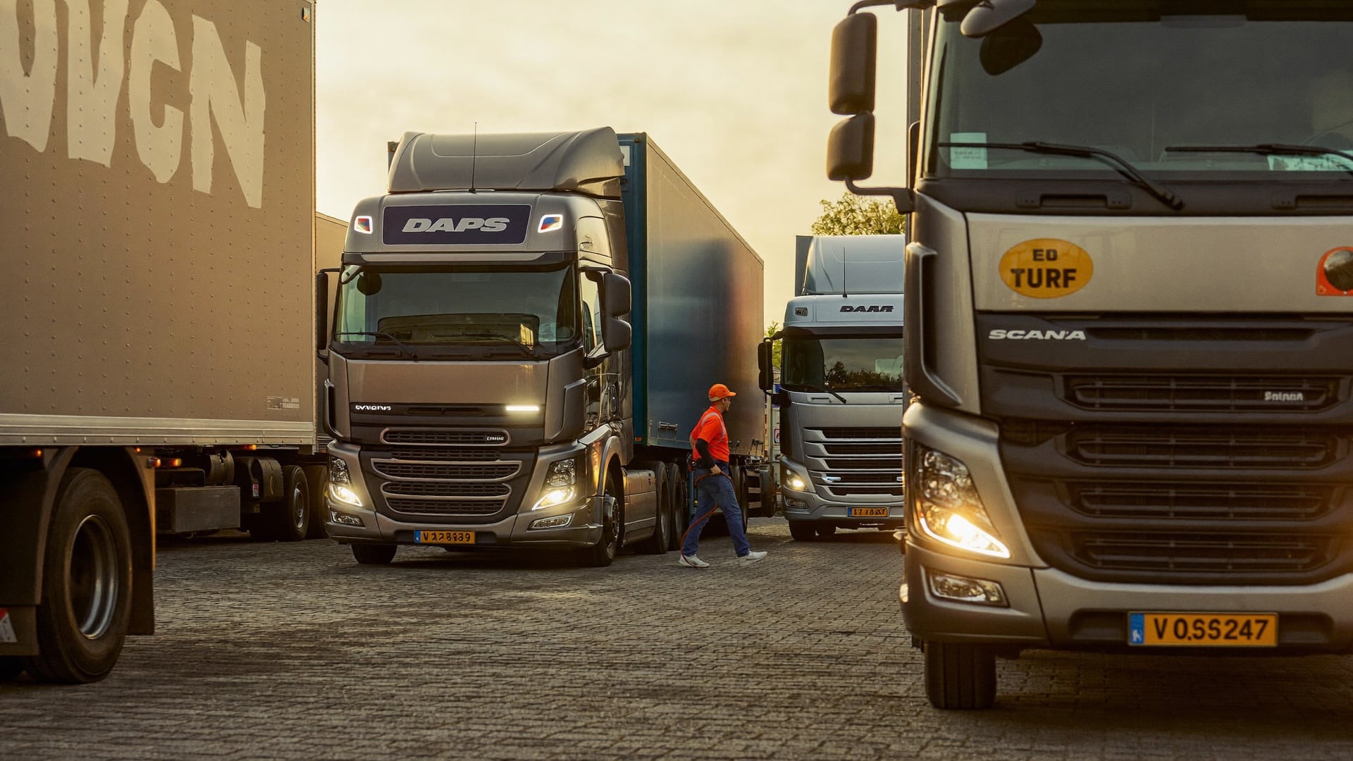 A fleet mechanic rolling a truck out of the bay at sunrise, maintenance complete